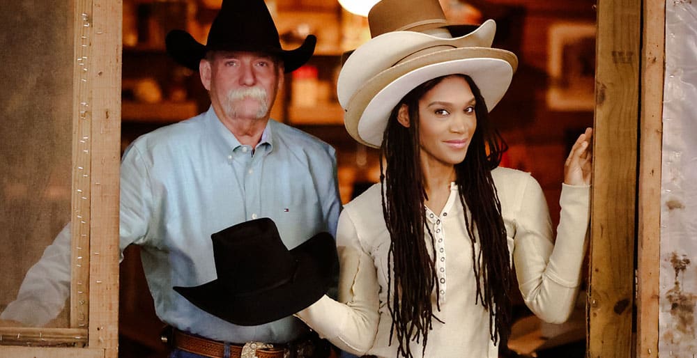 Una fotografía de un vaquero con un sombrero de vaquero negro, con una mujer con cuatro sombreros de color claro, posando.